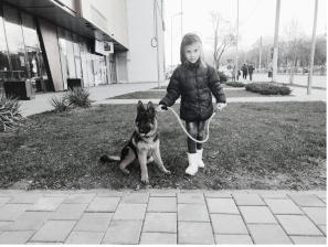 fetita cu pui ciobanesc german in lesa pe iarba